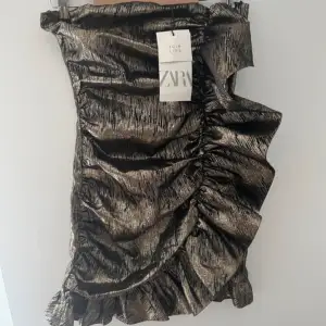 Superfin guldig klänning med volanger! Helt oanvänd då jag köpte två storlekar och säljer den som inte passade 💓Supersnygg och unik klänning!! Storlek XS