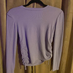 lila tröja - Lila fin tröja med snörning på sidorna. Tröjan är väl använd och lite nopprig men den är hel och har inga fläckar.