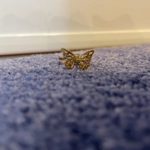 Fjärilsring - Jättefin fjärilsring som är använd men ändå fin. Fjärilen är guldglittrande och ringen är också guldfärgad. Den är inte så stor det är en lillfinger ring!