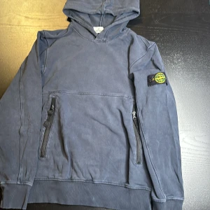 Navy Blue Stone Island Hoodie - Den är äkta från NK. Jag skickar mer bilder om ni frågar. Använd men i bra skick. Stilig och felfri. Säljer för att jag har växt ur den. Kontakta mig för mer information. Priset går att diskutera.