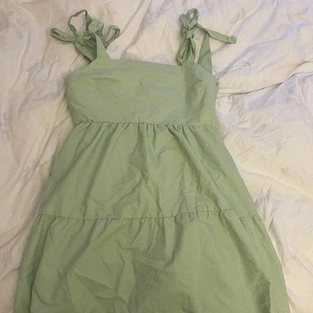 En grön klänning med volanger och knytning vid axlarna som är använd fåtal gånger.. Klänningar.