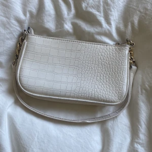 Vit läderväska - Supersnygg vit läderväska. Perfekt till vardagen. Finns liten ficka inne för exempelvis plånbok etc. Guld detaljer vid axelremmen. Pris kan diskuteras🤍