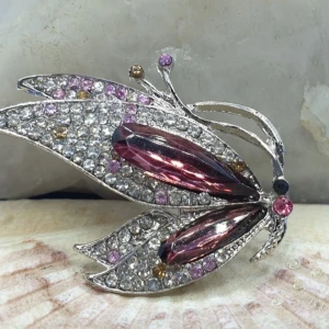 Brosch - Vacker Fjäril i rosa/lila - Den här broschen föreställer en fjäril och måtten är ca 4.5 ×3.5 cm. Silverfärgad metall med vacker ytstruktur och kristaller i flera färger, bl.a rosa/lila. Otroligt vacker brosch.