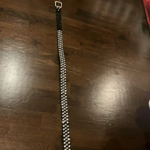 Glansigt bälte - Säljer detta bältet för att det inte min stil längre. Detta bältet är fullt av ”kristaller” som glänser. Längst ner på bältet är det läder. Längden är 107cm. Perfekt till lågmidjade jeans, jättefin och går att justera.💞