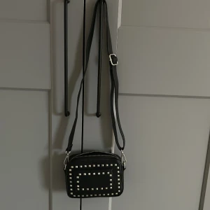 Svart väska - Svart väska med silvriga taggar, axelband kan ändras om man vill ha den längre eller kortare🖤🤍