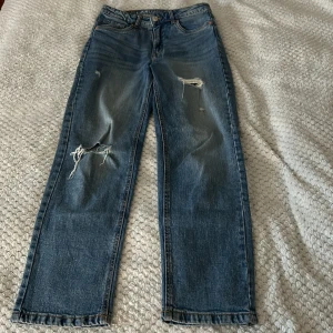 Blåa jeans - Säljer ett par blåa jeans med hål, från Kappahl, dem är 35cm i midjan och 96cm i längden, passa på