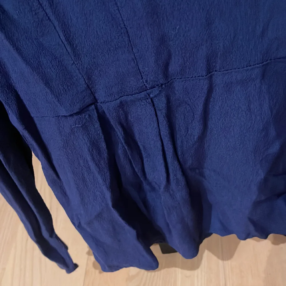 En jättefin blå blus med en liten volangkant. Dragkedja i bak Storlek 42. Puserot.