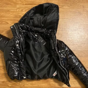 Svart glansig kort jacka  - Jätte snygg glansig din jacka , har en exakt lika Dan i annan storlek så denna hänger bara i garderoben 