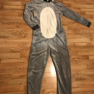 Onepece Grävling  - Supermysig grå mjuk heldress att ha hemma eller perfekt till maskeraden! Svans och grävling ansikte på huvan. Storlek 170. 