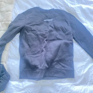 Sweatshirt  - En svart sweatshirt med liten vit text fram