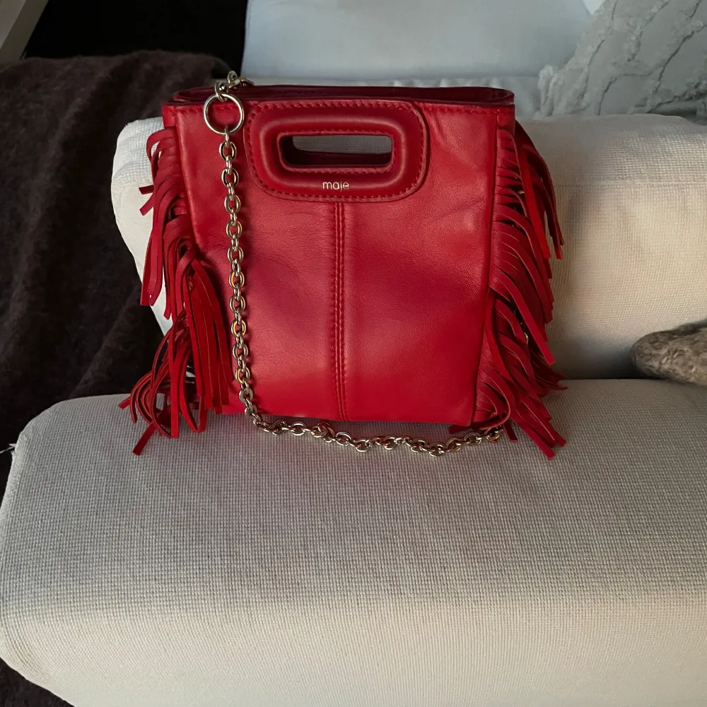 Säljer en röd liten maje väska med tillhörande kedja och band. Väskan är i nyskick och i läder material. Väskor.