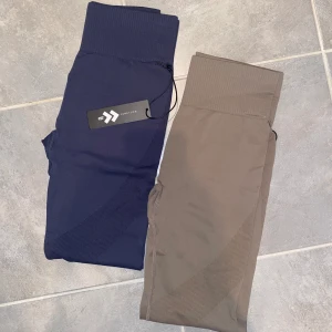 Träningstights blå och grå/beige  - Säljer två par träningtights från lager 157. Superskönt men tyvärr lite för små för mig. De blå är helt oanvända och de grå/beigea är använda en gång och tvättade. Säljer båda för 50kr tillsammans eller ett par för 30kr.