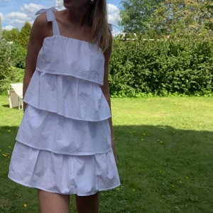 Studentklänning volang  - Drömmig vit volangklänning med band man knyter vid axlarna. Perfekt till student, skolavslutning eller midsommar! Helt ny med prislapp kvar och oanvänd, endast provad. Från Bohoo. Ej genomskinlig. 
