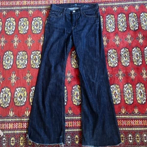 Mörkblå jeans - Jättesnygga mörkblå utsvängda jeans från 7 For All Mankind. Står ingen storlek men skulle säga att storleken är en S