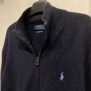 Polo Ralph Lauren Full-zip - Mörkblå stickad full-zip från Ralph Lauren, storlek S. Bra skick, nypris runt 2500.