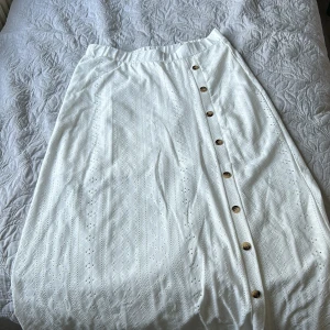 En lång vit kjol! - En lång vit kjol som har slit på sidan tillsammans med knappar! Kjolen har även en underkjol alltså är den ej genomskinlig. Den har aldrig använts! 