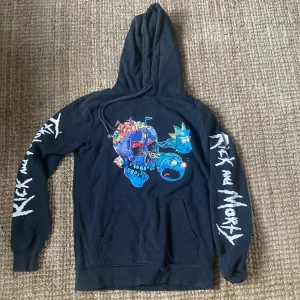 Hoodie med tryck - Hoodie från H&M. Tryck Rick snd Morty. Lite urtvättad och muddar ytterst lite slitna men annars i fint skick. 