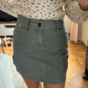 Minikjol cargokjol - Superfin, lite blårandig. Tum 26 i midjan, säljer pga passar ej. Från märket Caterpillar, 100% bomull.