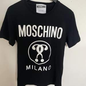 Nu säljer vi en riktigt fet T-shirt från Moschino för 299kr. Storlek: S, Skick: 7,5/10