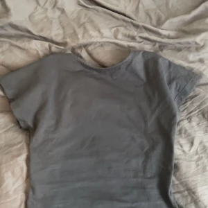 T-shirt med öppen rygg - Säljer den skitsnygga trendiga mörkgrå t-shirten med öppen rygg från Motel Rocks. Perfekt nu till sommarn😍 Den är i strl S. Säljer då den inte kommer till användning. Hör av dig vid frågor och funderingar samt innan du köper🥰