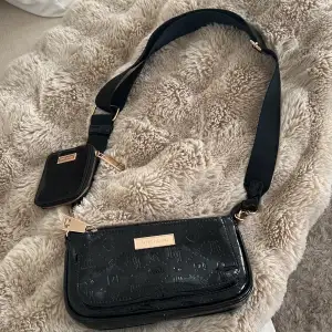 Säljer denna svarta Cross body bag med guld detaljer. Bandet går att reglera längden på. Knappt använd, som ny. Säljer för 350 kr. Köparen står för frakten!