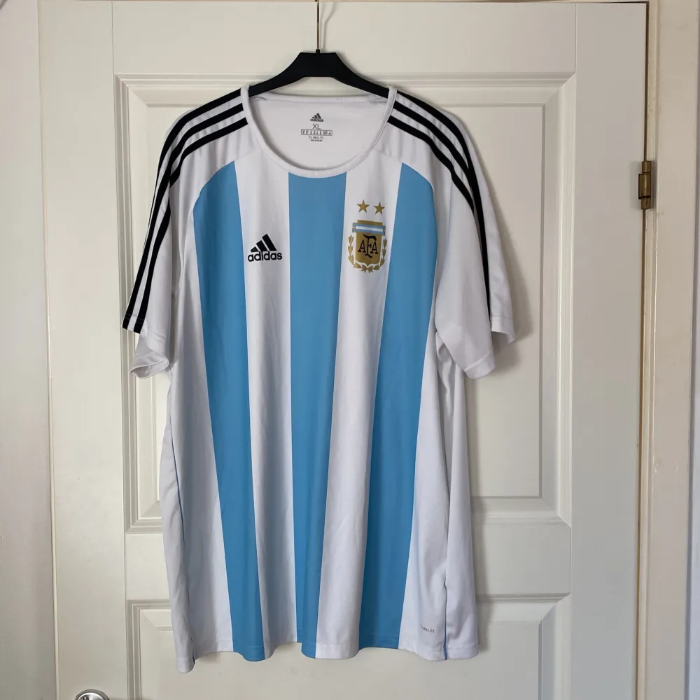 En riktig fin Argentina Fotbollströja. Tröjan är i toppskick! OBS! Märkena på tröjan är tryckta och inte sydda (ej autentisk/äkta). Tveka att inte att kontakta mig vid frågor eller funderingar.. T-shirts.