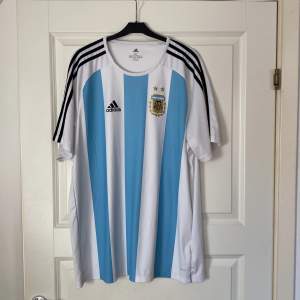 En riktig fin Argentina Fotbollströja. Tröjan är i toppskick! OBS! Märkena på tröjan är tryckta och inte sydda (ej autentisk/äkta). Tveka att inte att kontakta mig vid frågor eller funderingar.