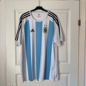 Argentina Fotbollströja - En riktig fin Argentina Fotbollströja. Tröjan är i toppskick! OBS! Märkena på tröjan är tryckta och inte sydda (ej autentisk/äkta). Tveka att inte att kontakta mig vid frågor eller funderingar.