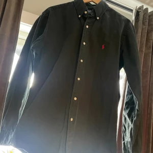 Ralph lauren skjorta  - Svart Ralph lauren skjorta i storlek M. Den är använd en del men skicket är ändå bra skulle jag säga.