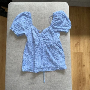 Blå topp  - En blå topp med snörning bak, köpt förra sommaren. Säljer den då den inte kommit till användning, använd fåtal gånger och i fint fick. Är i storlek M men passar den som har S. 