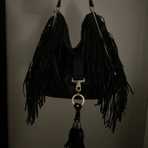 Väska med fransar - Väska med fransar och ett hänge. Man kan dock stoppa in hänget i väskan så det inte syns, som jag gjort på bild 2 💕 bild 3 är baksidan. Den rymmer sjukt mycket 🙌