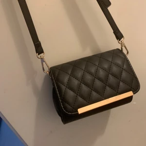 Snygg axelremsväska - Helt nya, har 3 par. Guldig design, söt och prydlig. Telefon,kort nyklar osv passar perfekt i den. En väska som passar allt och bär det du behöver. Pris kan diskuteras.
