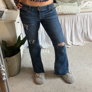Lågmidjade jenas - Supersnygga lågmidjade jeans med slitningar i nyskick! Står ingen storlek men skulle säga 38/40 med midjemått 44 cm