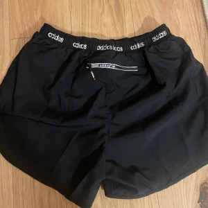 Adidas Training shorts  - Nya endast prövade små i Stl är som Stl L men står 2-XL har en ficka bak med dragkedja ,snygg look med sprud i sidorna för en ökad rörelse frihet. Elastisk resår i midjan med snören