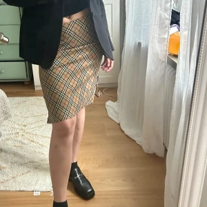 Stretchig kjol i rutmönster - Kjol i rutat mönster i fint skick med slitsar på sidorna.