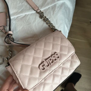 Handväska - Söt handväska från Guess. Mer ljusrosa i färgen än bilden visar. Lite sliten, se första bilden. 