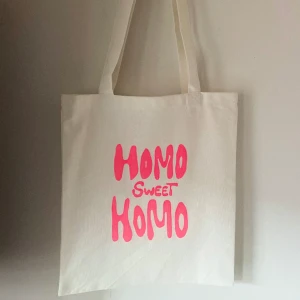 Tygkasse, tygväska, tygpåse  - Handsydd tygkasse med motivet ”homo sweet homo”.   Tillverkad i 100% återvunna textilier. Motivet är handmålad med textilfärg.   Mått: 32x35 cm  Hämtas på Södermalm alternativt skickas med post. 