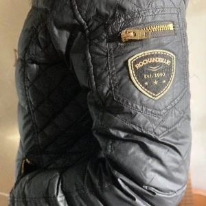 Rock and blue -  Jag är 160 cm och jackan går ner till knäna på mig.  Jackan har svart äkta päls. Dragkedjan är lite trög och kan behöva oljas ev bytas. Använd en vinter och köptes för 4500 kr