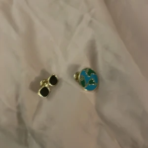 5kr smycken! - I den första bilden ser man såna saker man sätter på väskor som kostar 5kr styck.  På den andra Bilden så ser man ett par jul örhängen utan plupp som kostar 15kr. På den sista bilden så ser man en hårklämma med mönster som kostar 5kr.