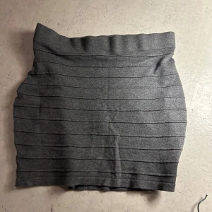 Grå kortkjol  - Säljer en grå, tight kortkjol med horisontella ränder. Kjolen har en enkel och stilren design, perfekt för att matcha med olika toppar. Materialet är mjukt och stretchigt för en bekväm passform.