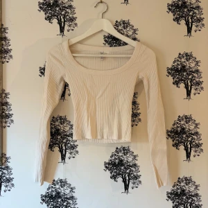 Vit ribbad topp från H&M Divided - Säljer en vit ribbad topp från H&M Divided i storlek XS. Toppen har lång ärm, croppad passform och en bred, rundad halsringning. Materialet är mjukt och stretchigt, perfekt för att styla med jeans eller kjol. Enkel och clean look som funkar året runt.