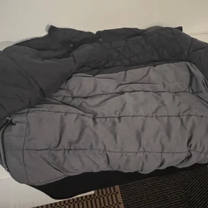 Svart och grå pufferjacka från H&M - Säljer en svart och grå pufferjacka från H&M med hög krage och två sidofickor med dragkedja. Jackan har quiltad design och hel dragkedja framtill. Perfekt för kalla dagar och har en clean, modern look. Jackan Luva finns också 👍