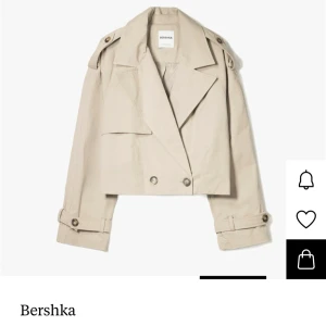 Beige croppad trenchcoat från Bershka - Snygg croppad trenchcoat från Bershka i beige med breda slag, dubbelknäppning och detaljerade axelpartier. Jackan har långa ärmar med spännen vid armslutet💕