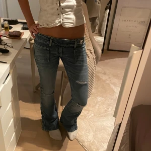 Lågmidjade blå bootcut jeans - Populära Gina jeans med coola detaljer och slitningar. Mycket bra skick knappt använt