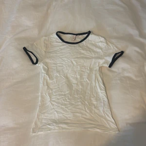 Vit t-shirt med svarta detaljer - vit t-shirt med svarta kantband vid halsringning och ärmslut