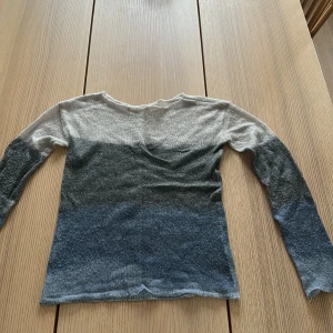Randig långärmad tröja Pull&Bear XS💖 - Säljer en tunn, stickad långärmad tröja från Pull&Bear i storlek XS. Tröjan har breda horisontella ränder i grått, mörkgrått och blått. Perfekt för lager-på-lager och chill stil. Materialet är mjukt och lätt, med enkel rund hals.