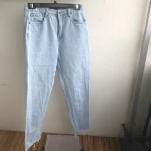 Ljusblå jeans  - Säljer ett par ljusblå jeans med raka ben  , fransiga längst nere. Jeansen har klassisk femficksdesign och stängs med knapp och dragkedja. 