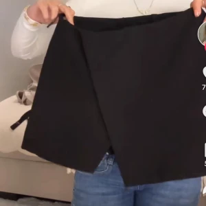 Svart omlottkjol i enkel design - Svart omlottkjol med stilren och minimalistisk look. Kjolen har en rak passform och är perfekt för dig som gillar en clean och klassisk vibe. Enkel att matcha med både sneakers och boots.