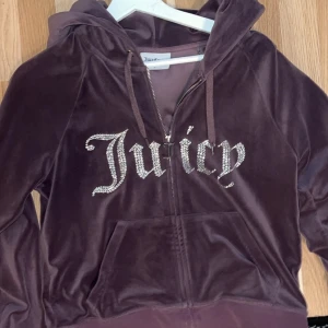 💜 lila velour hoodie Juicy Couture - Säljer en lila hoodie från Juicy Couture i mjuk velour med glittrande Juicy-text på bröstet. Tröjan har huva, snörning och dragkedja framtill samt en stor ficka. Perfekt för dig som gillar klassisk Y2K-stil.
