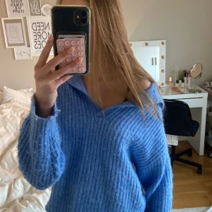 Blå stickad tröja från Gina Tricot - Supermysig blå stickad tröja från Gina Tricot med krage och v-ringad hals. Tröjan har långärmade ribbade muddar och en loose passform.